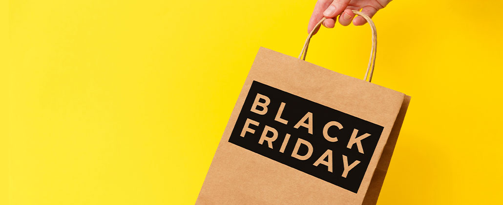 Saco de compras com a mensagem "Black Friday", fundo amarelo atrás